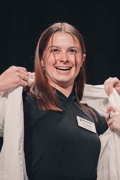 A student graduates and earns her white coat.